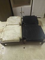 Four wooden footstools with two black and two off-white cushions