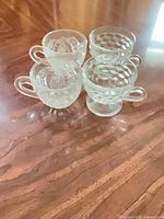 All four clear pressed glass sherbet cups grouped on table