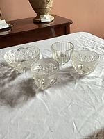 All four clear pressed glass cups displayed together
