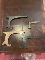 Four brackets laid flat showing size and finish differences