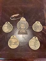 All five medallions displayed, showing both sides and plaques