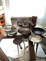 Overview of five pans, lids, box, manual