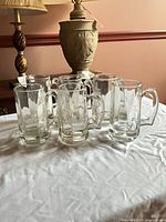 All six clear glass faceted beer mugs grouped on table