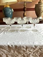 Group of six crystal diamond-cut coupe glasses on table