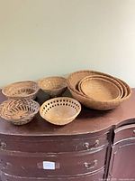 Seven wicker baskets of varied sizes on dresser