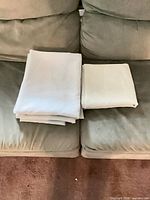 Four folded ivory/cream sheer panels on couch