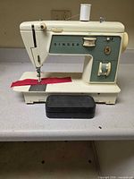 Full view of Singer 717 sewing machine with accessory box and thread spool on countertop