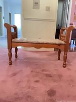 Front view of solid wood bench showing arms, legs, seat and cushion