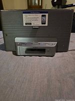 Front view showing speaker grille, 30-pin dock, LCD display and attached power cord