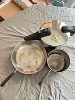 Top view of frying pan, saucepan and pressure cooker showing handles and interiors