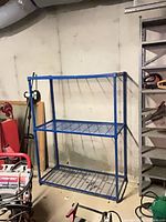 Full view of one blue steel shelving unit showing three wire shelves