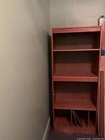 Front view of tall cherry-tone bookcase showing shelves and lower compartment