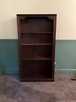Front view of dark brown wood veneer bookcase with three interior shelves and base shelf