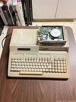 Tandy 1000 computer with drive sitting on top, showing missing bay covers and detached drive