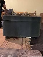 Side view of teal ottoman showing upholstery and wheels