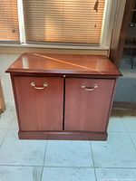 Front view of cherry veneer cabinet with closed doors and brass handles