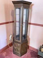 Closed view of corner curio cabinet showing glass door panels and dark brown wood finish