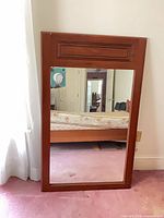 Full view of mirror leaning against wall, showing frame and glass