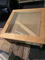 Top view showing square frame, glass insert, engineered wood surface