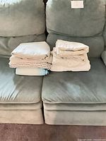 Two stacks of folded fitted sheets on sofa