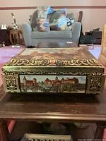Front view of brass gilt vanity box with painted architectural panel and ornate repoussé
