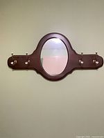 Full view of wall mirror with hooks mounted on wall
