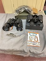 Full lot view showing both binoculars, goggles box, multi-tool and carded carabiners