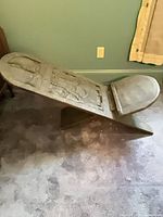 Side view of carved wooden African bench showing folding X-base