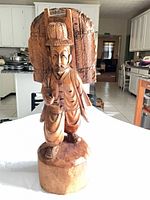 front view of carved wood figurine standing on round base