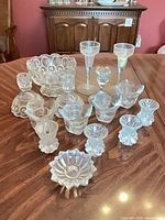 Group shot of all 15 pressed glass candlesticks, votives and bowl