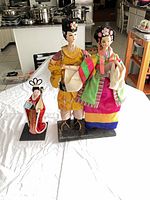 Overview of three East Asian dressed dolls on bases