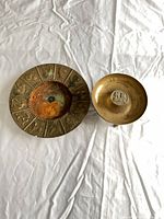 Both brass bowls/ashtrays side by side showing size difference and patina