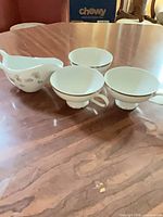 Group shot showing three teacups and creamer on table