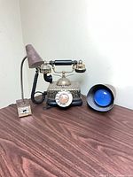 Telephone centered, gooseneck lamp left, cone lamp right