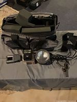 All items laid out: camera bag with foam dividers, Vivitar 3200 flash on box, handheld spotlight, Epson viewfinder, strap