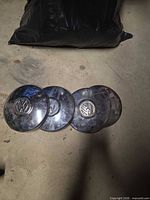 Four chrome VW center caps laid on concrete floor