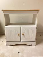 Front view of white cabinet showing natural wood top, open shelf and double doors