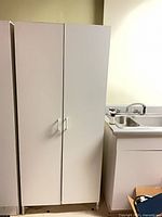Closed white double-door wardrobe beside sink