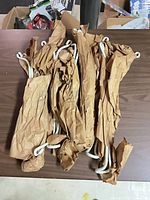 Group of eight white plastic plant hanger hooks in packing paper