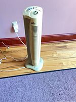 Full view of beige WindChaser tower fan standing on hardwood floor with power cord connected