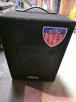 Front view of Yamaha S12e speaker showing grille, badge and model decal