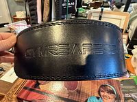 Front of black leather belt showing embossed Gymreapers logo and stitching