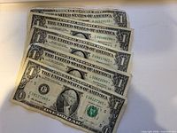 All five $1 star note bills fanned out, showing serial numbers and condition