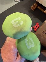 Two green neoprene dumbbell ends showing white G logos and surface wear