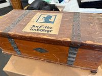 Closed wooden box showing paper soldier graphic and metal straps
