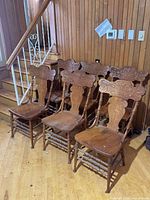Six matching carved press-back chairs lined up