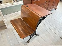 Angled overview of desk showing wood seat, backrest, desktop and iron frame