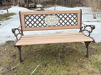 Front view of cast iron and wood garden bench on grass and snow background