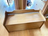 Top view of wooden storage bench showing lid seam and curved side arms