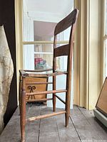Left side view of bare wooden chair showing missing seat and frame condition